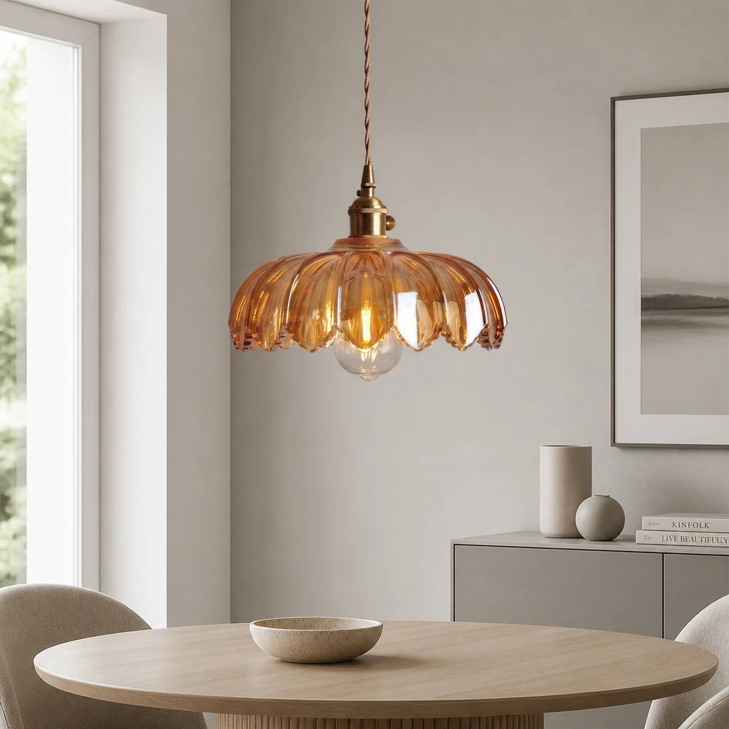 Kyler amber ribbed glass pendant light glowing above a dining table beside a window