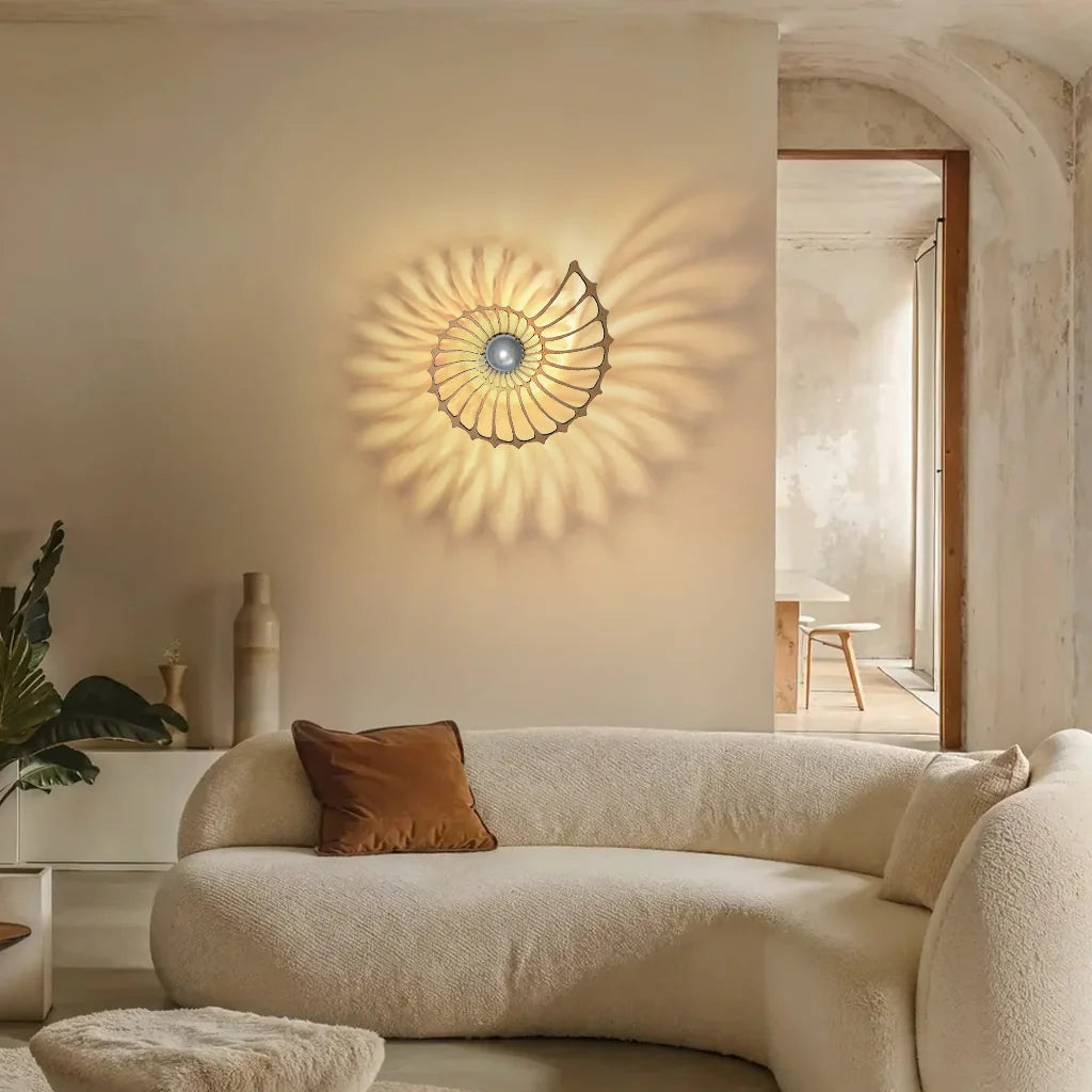 Large Nautilus shell wall sconce acting as a striking focal point above a curved beige sofa