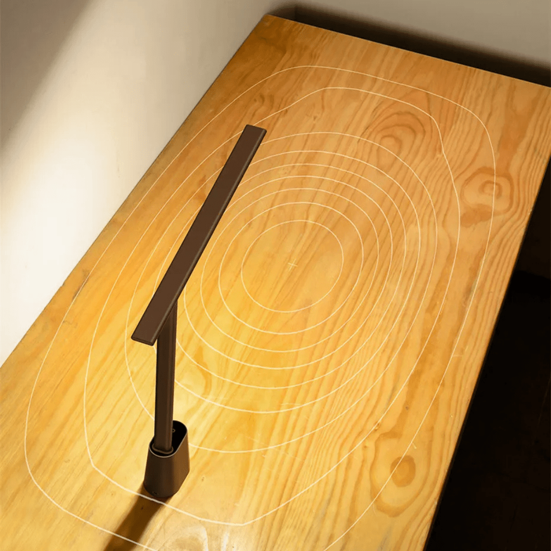Graphic demonstrating the wide, even light coverage of the foldable LED desk lamp on a wooden desk