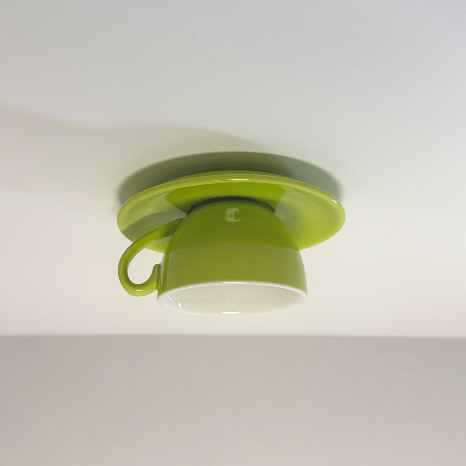Light green playful coffee cup ceiling fixture mounted flush against a ceiling