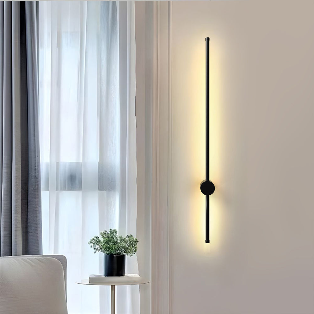 Long black LED tube wall light mounted vertically next to sheer curtains in a bright, modern room