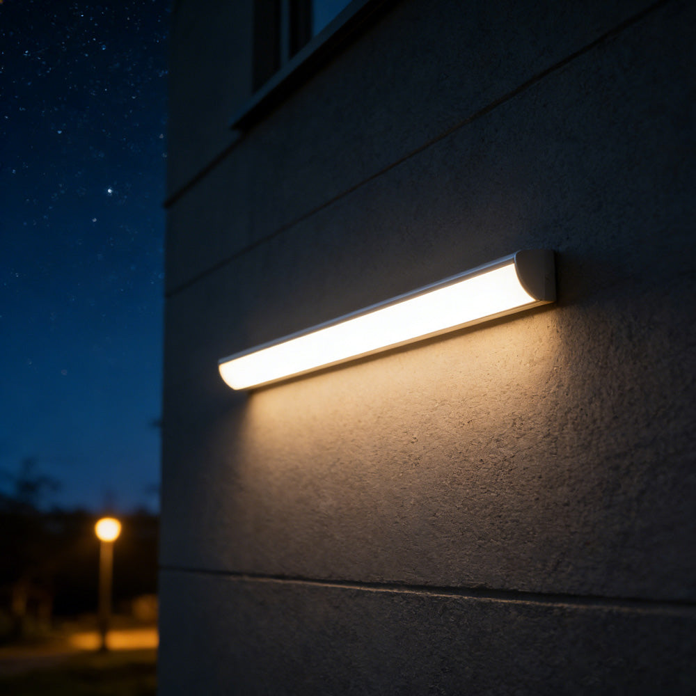 Long luminous LED bar mounted horizontally on a dark architectural outdoor wall
