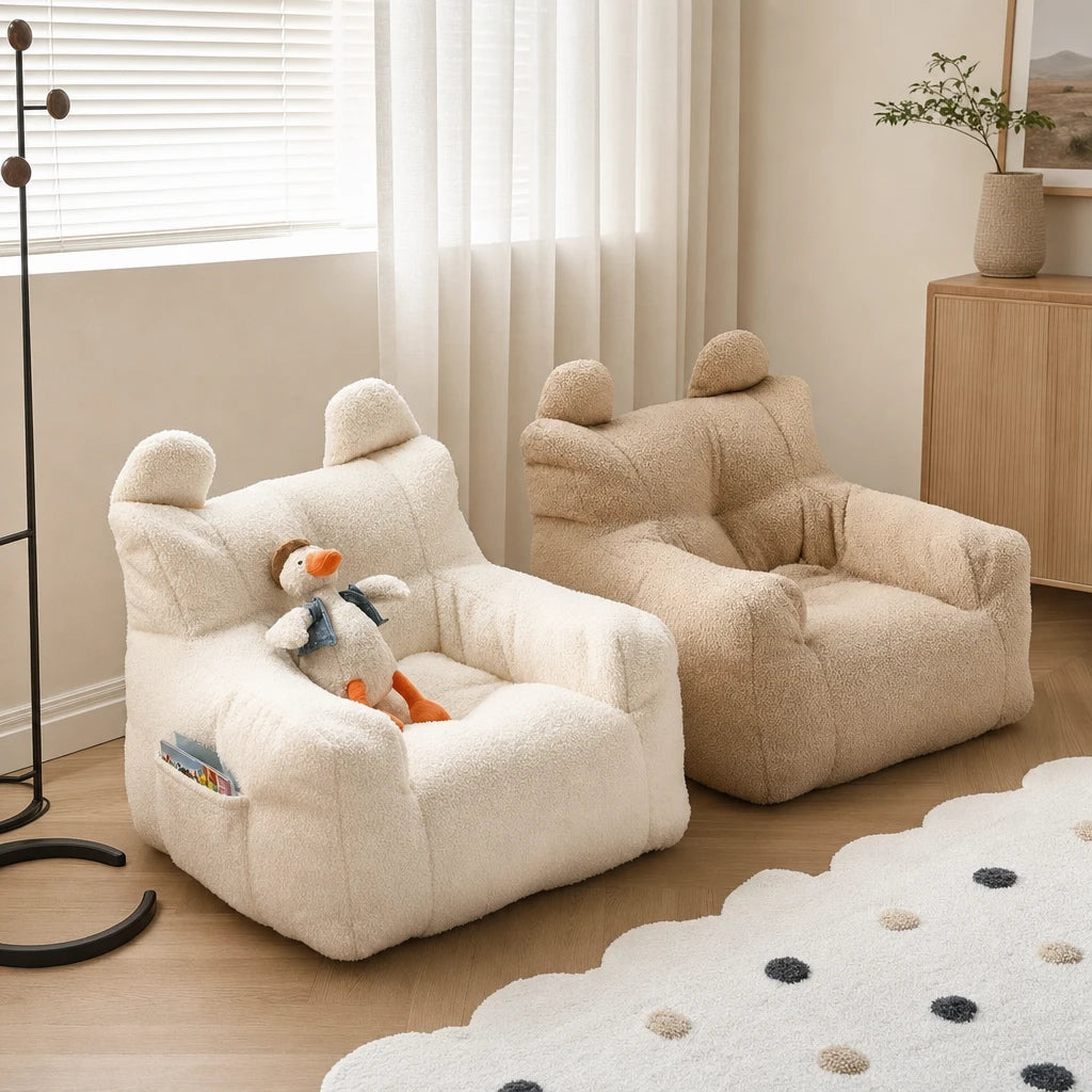 Cream and beige cartoon bear kids bean bag armchairs side by side in a modern minimalist playroom with a duck plush toy and spotted rug