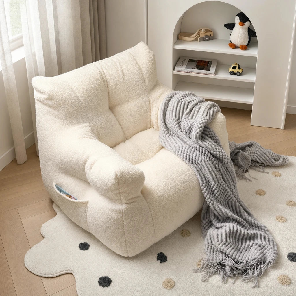Close-up of the cream Lydel kids bean bag armchair with a grey chunky-knit throw blanket draped over the armrest