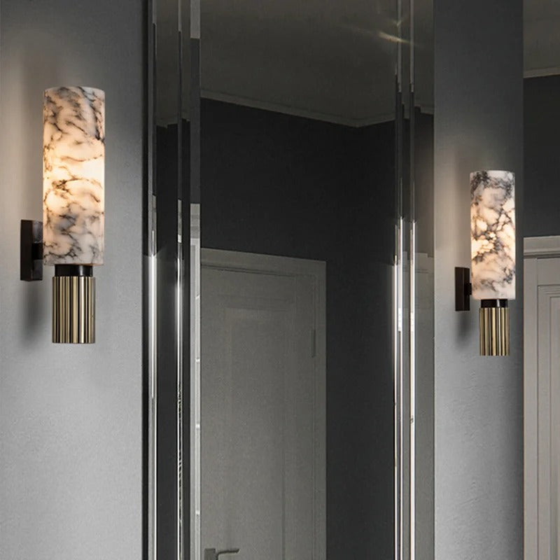 Marble cylinder wall sconce casting a soft ambient glow in a contemporary mirrored hallway