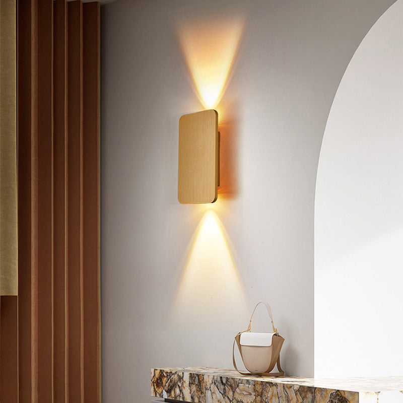 Modern mazka gold rectangular LED wall sconce casting a warm up and down light in a minimalist living room