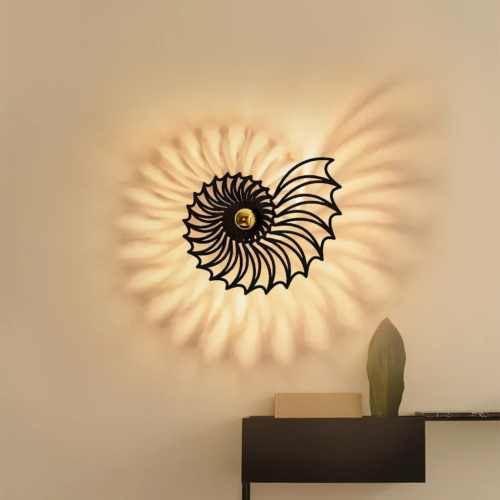 Medium black spiral metal wall light styled over a floating shelf in a modern interior