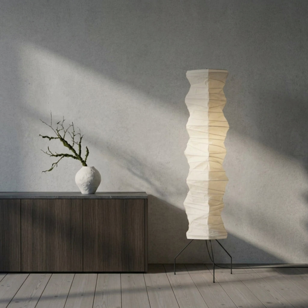 Close-up of the Mepzo floor lamp glowing beside a console table with a vase in a dimly lit room