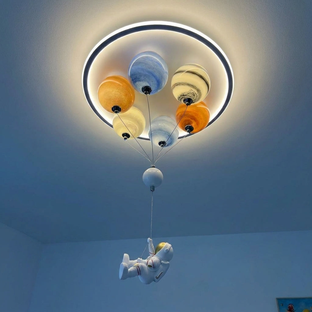 Close-up of the Meqzi ceiling light glowing warm white, with the resin astronaut figure hanging below the planets