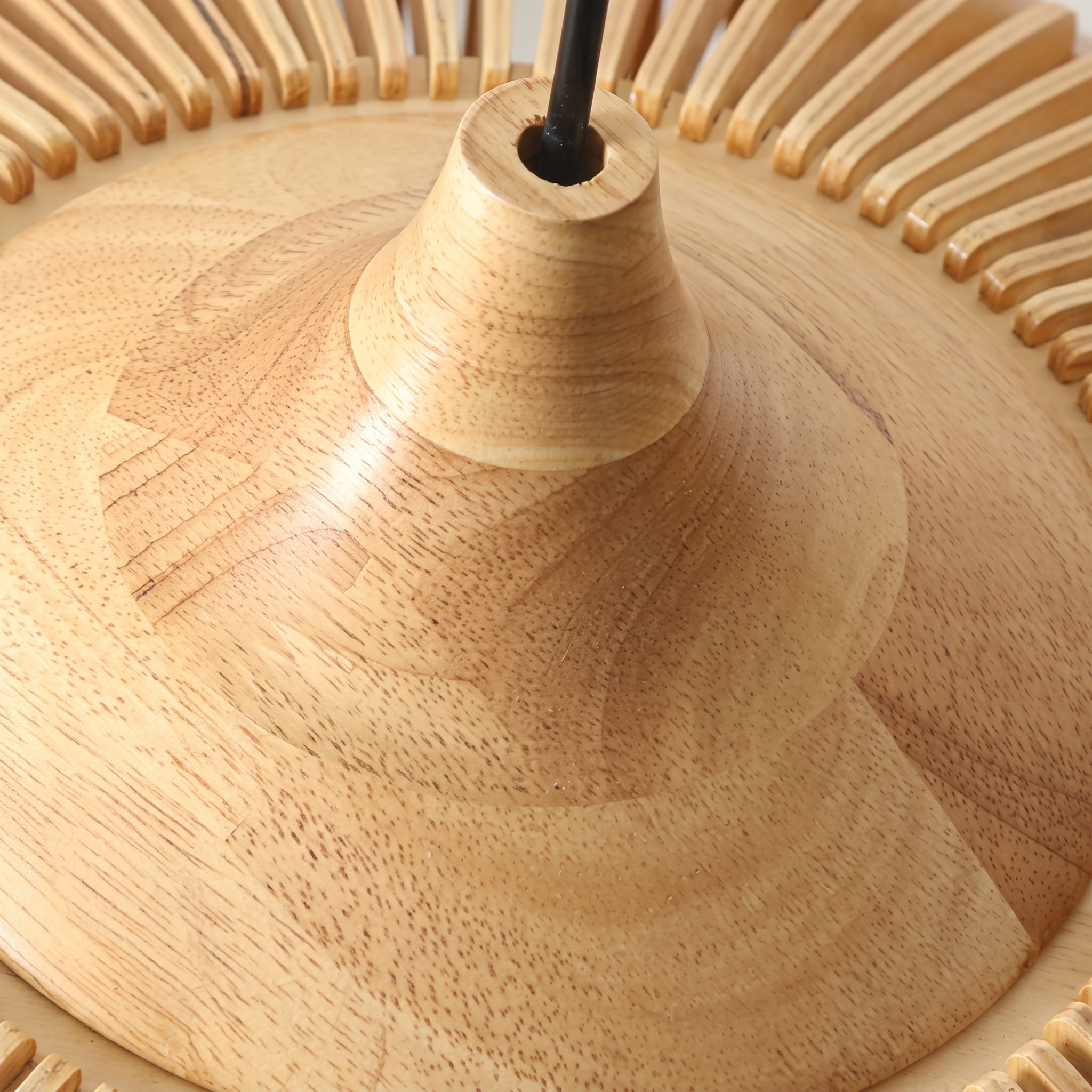 A close-up detail of the Modern Japandi slatted wood mexi pendant light in a natural finish, focusing on the smooth, turned wood top section where the black suspension cable connects