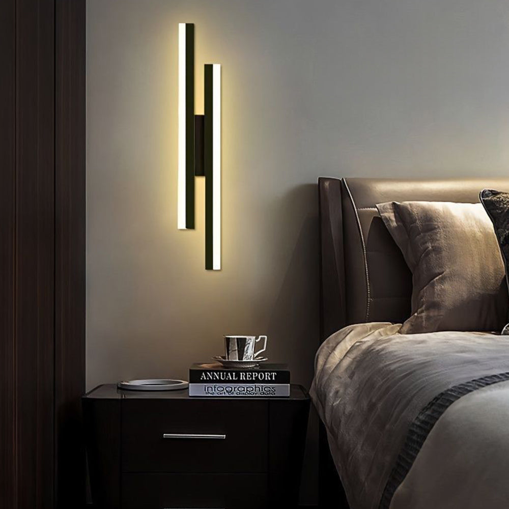 Black milor staggered linear wall lighting creating a moody, relaxing atmosphere above a bedside nightstand