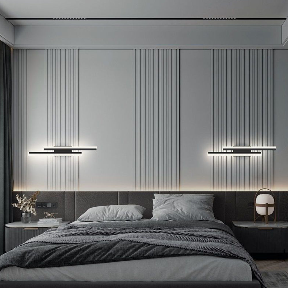 Pair of modern black milor staggered linear wall sconces mounted horizontally above a bedroom headboard