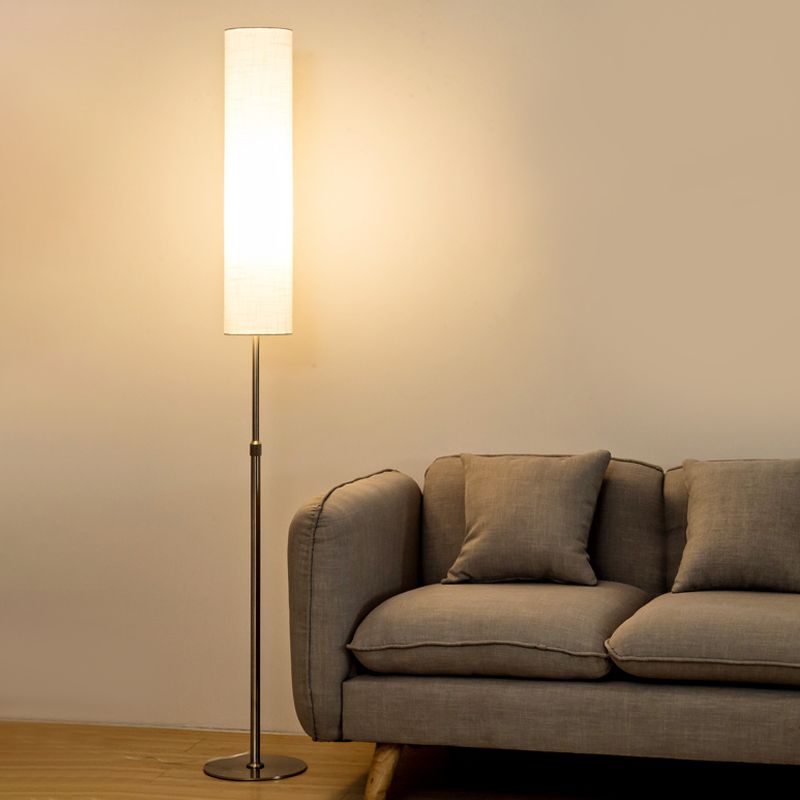 Minimalist standing light with a white fabric shade next to a modern grey sofa