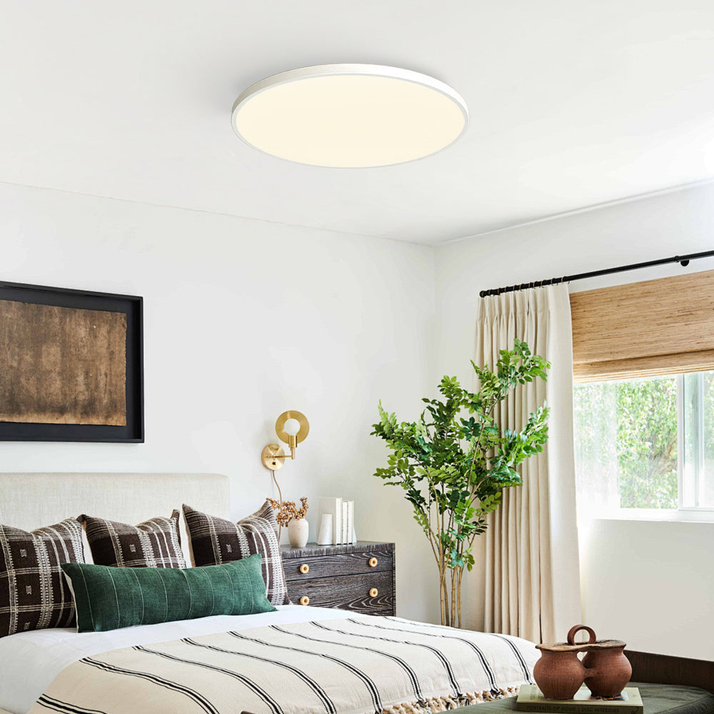 Minimalist white round ceiling light providing soft illumination in a bedroom decorated with greenery