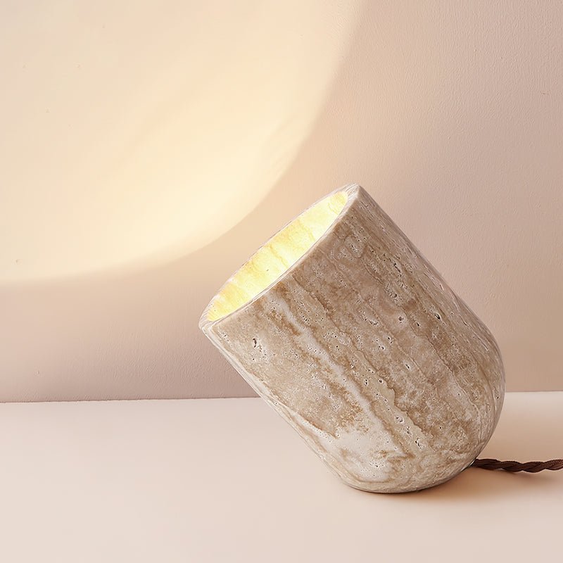 Natural yellow travertine misa table lamp casting a warm, glowing uplight against a minimalist background