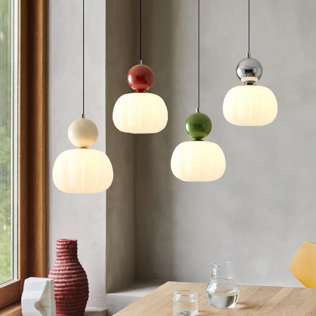 Mixed colour Art Deco pendant lights creating a playful, modern aesthetic over a wooden table