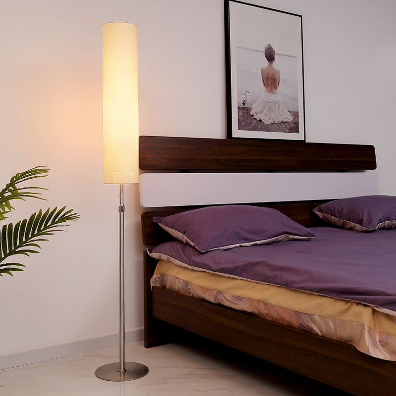 Modern cylindrical floor lamp providing relaxing ambient lighting in a contemporary bedroom