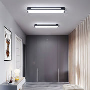 Two modern black linear LED flush mount ceiling lights illuminating a contemporary minimalist hallway