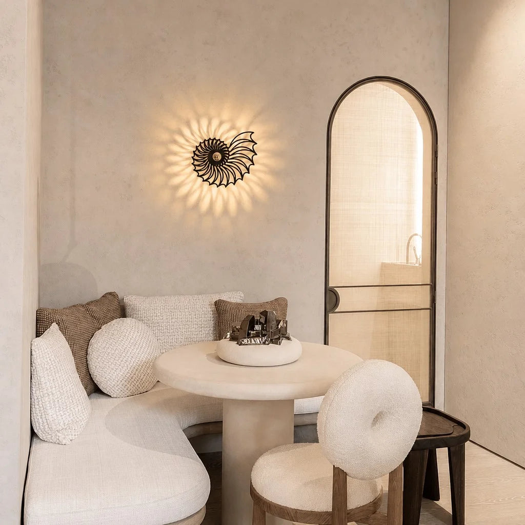 Modern black shell-inspired wall sconce illuminating a cosy beige lounge seating area