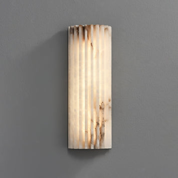 Modern fluted alabaster LED wall sconce highlighting its natural ribbed texture and glowing marble veining