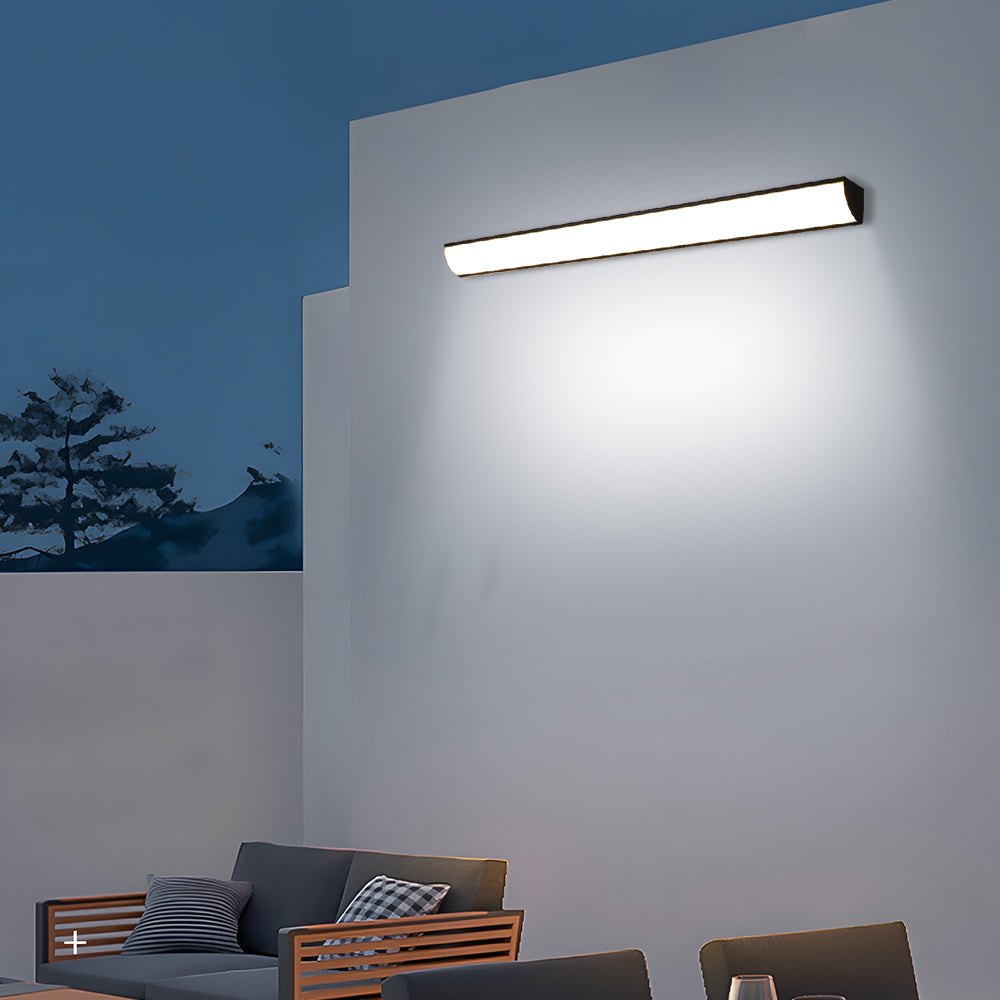 Modern long outdoor wall sconce providing bright ambient illumination at dusk
