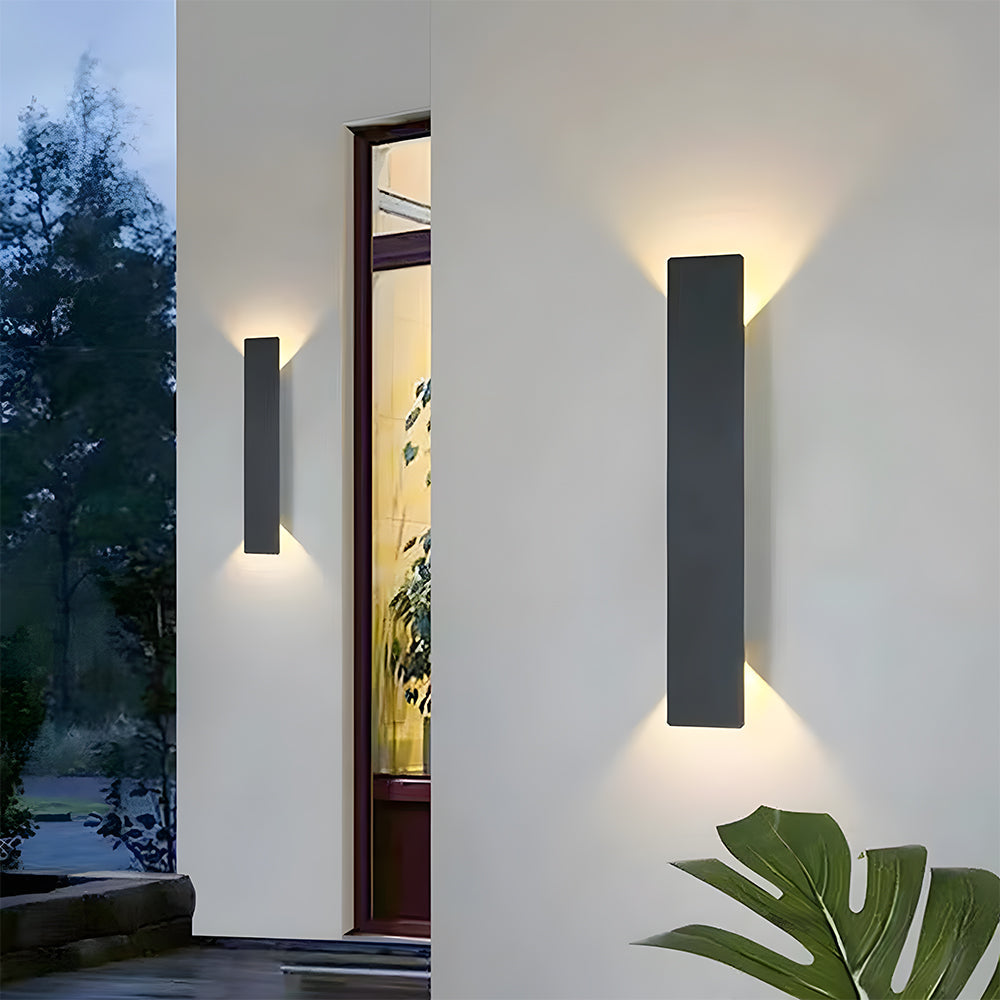 Modern slim black LED outdoor wall light casting up and down illumination on a white exterior wall