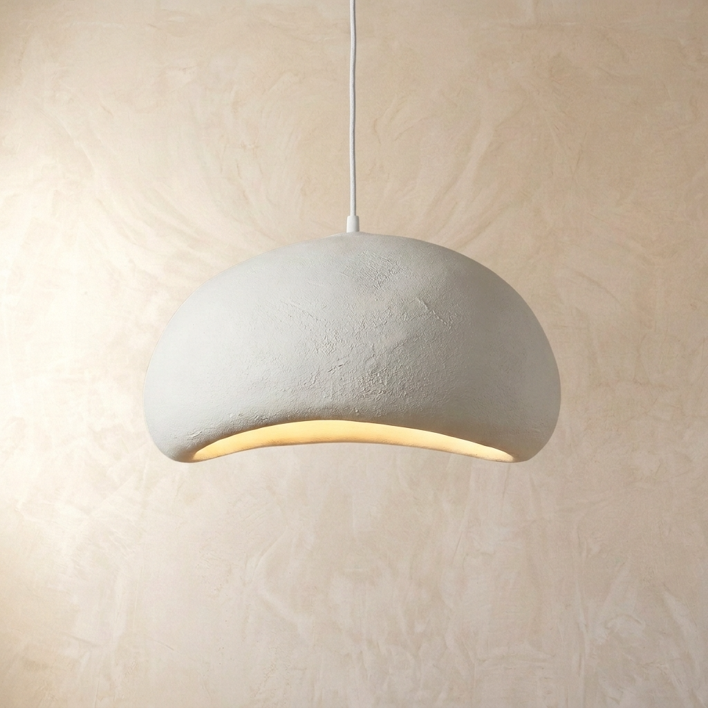 Modern white resin Wabi-Sabi pendant light with an asymmetrical design hanging against a textured wall