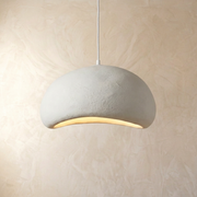 Modern white resin Wabi-Sabi pendant light with an asymmetrical design hanging against a textured wall