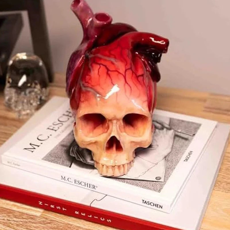 Necrovalve anatomical heart and skull resin ornament displayed on stacked books on a desk