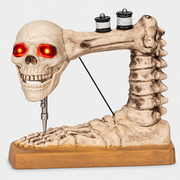 Close up of Needler skeleton sewing machine ornament showing glowing red eyes and needle