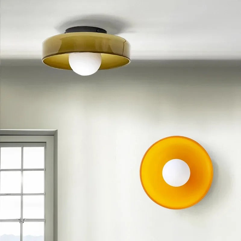 Vibrant orange and olive green glass wall sconce casting a warm ambient glow in a contemporary hallway