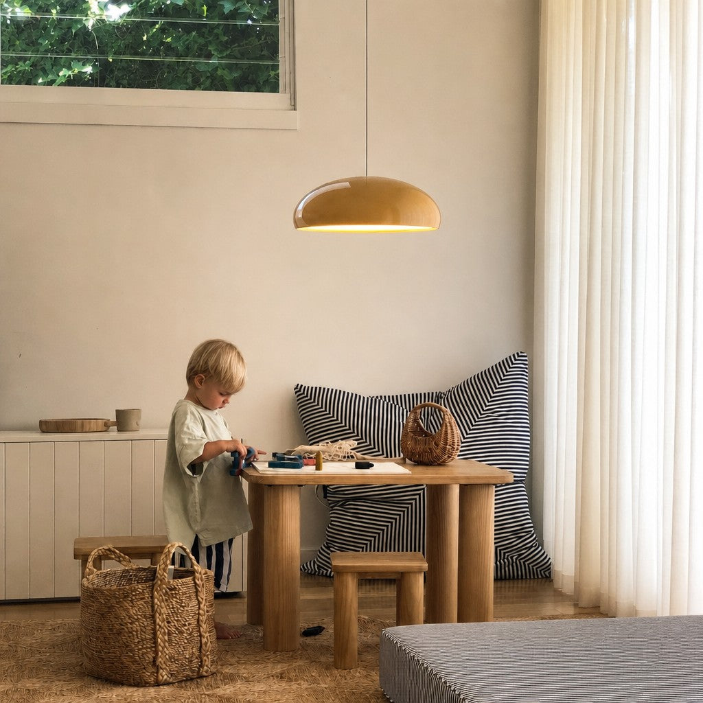 Orange Bauhaus dome pendant light illuminating a child's wooden play table in a bright room