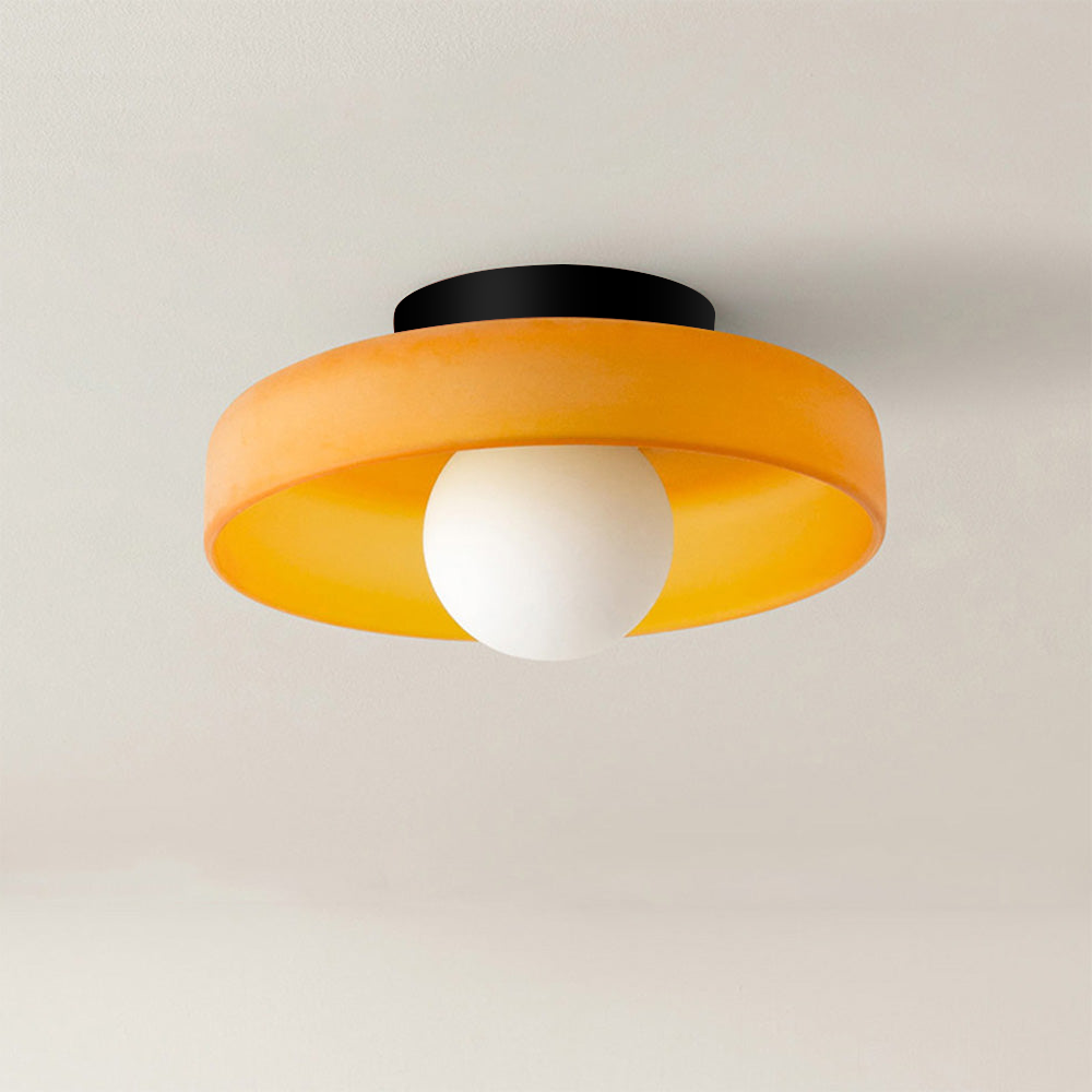 Orange glass disc ceiling light with an opal globe isolated on a light background