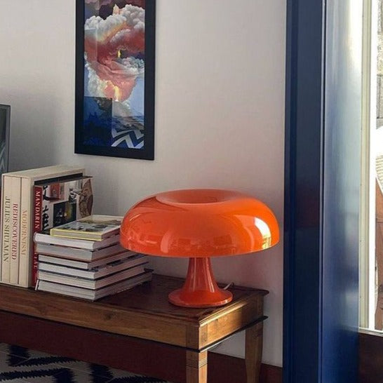 Orange mid-century dome table lamp providing a pop of retro colour on a wooden side table in a bright room