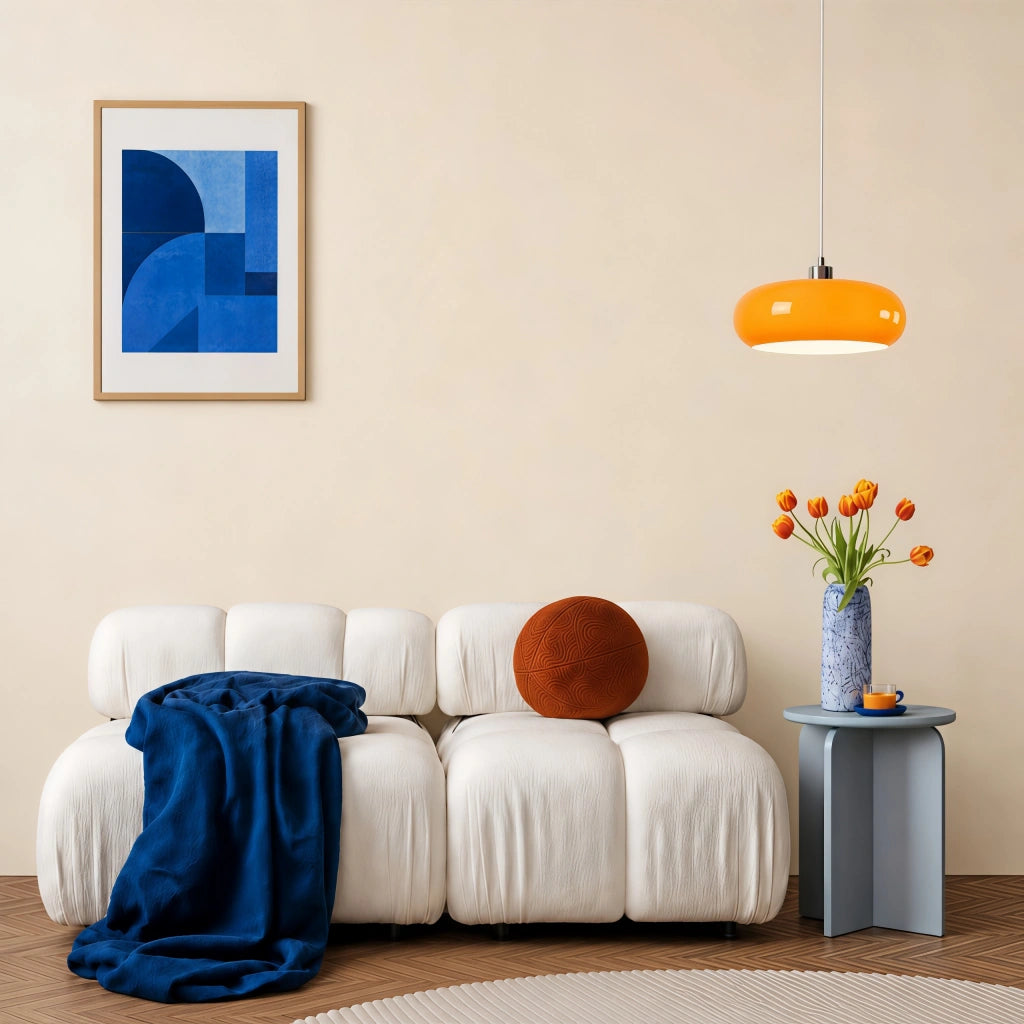 Orange Nordic glass pendant acting as a vibrant accent light over a white ribbed living room sofa