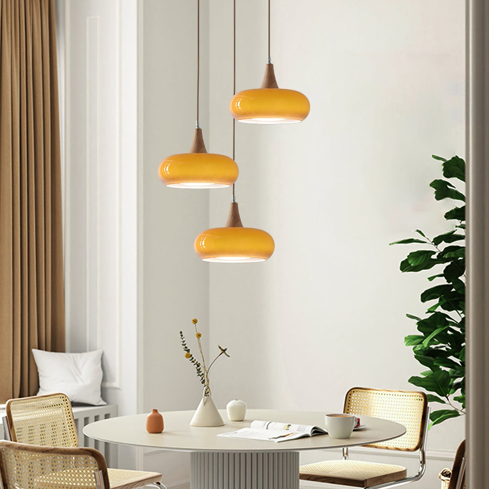 Three orange retro glass pendants suspended at staggered heights over a round dining table