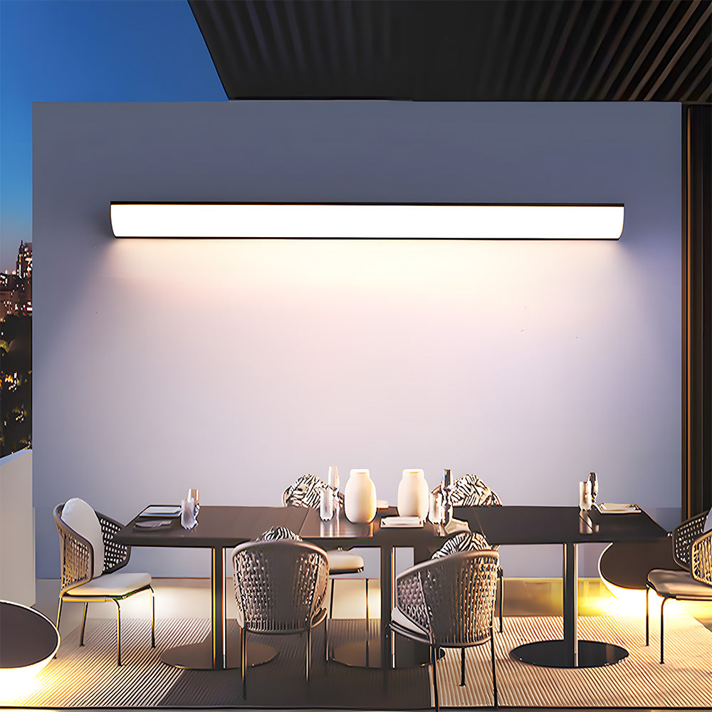 Long linear outdoor wall light illuminating an elegant alfresco dining table setting