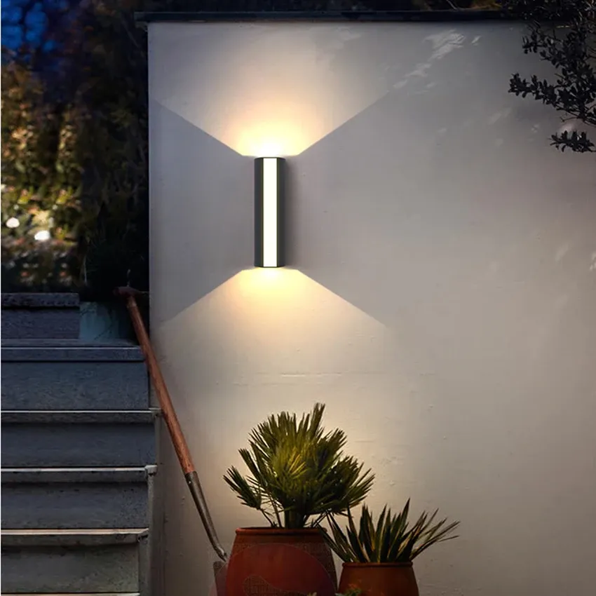 Modern outdoor LED sconce illuminating a garden staircase and potted plants at night