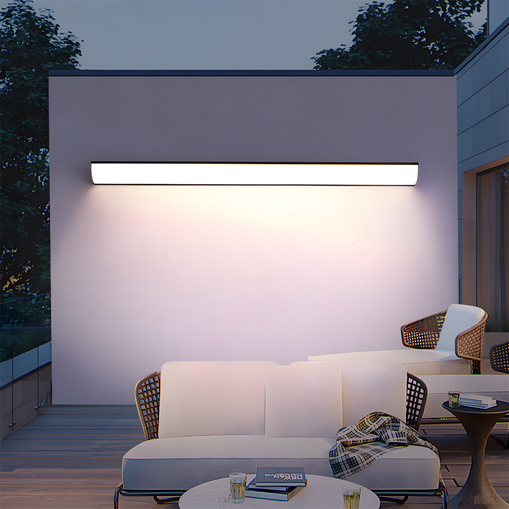 Modern linear wall sconce providing bright illumination over a comfortable outdoor patio sofa