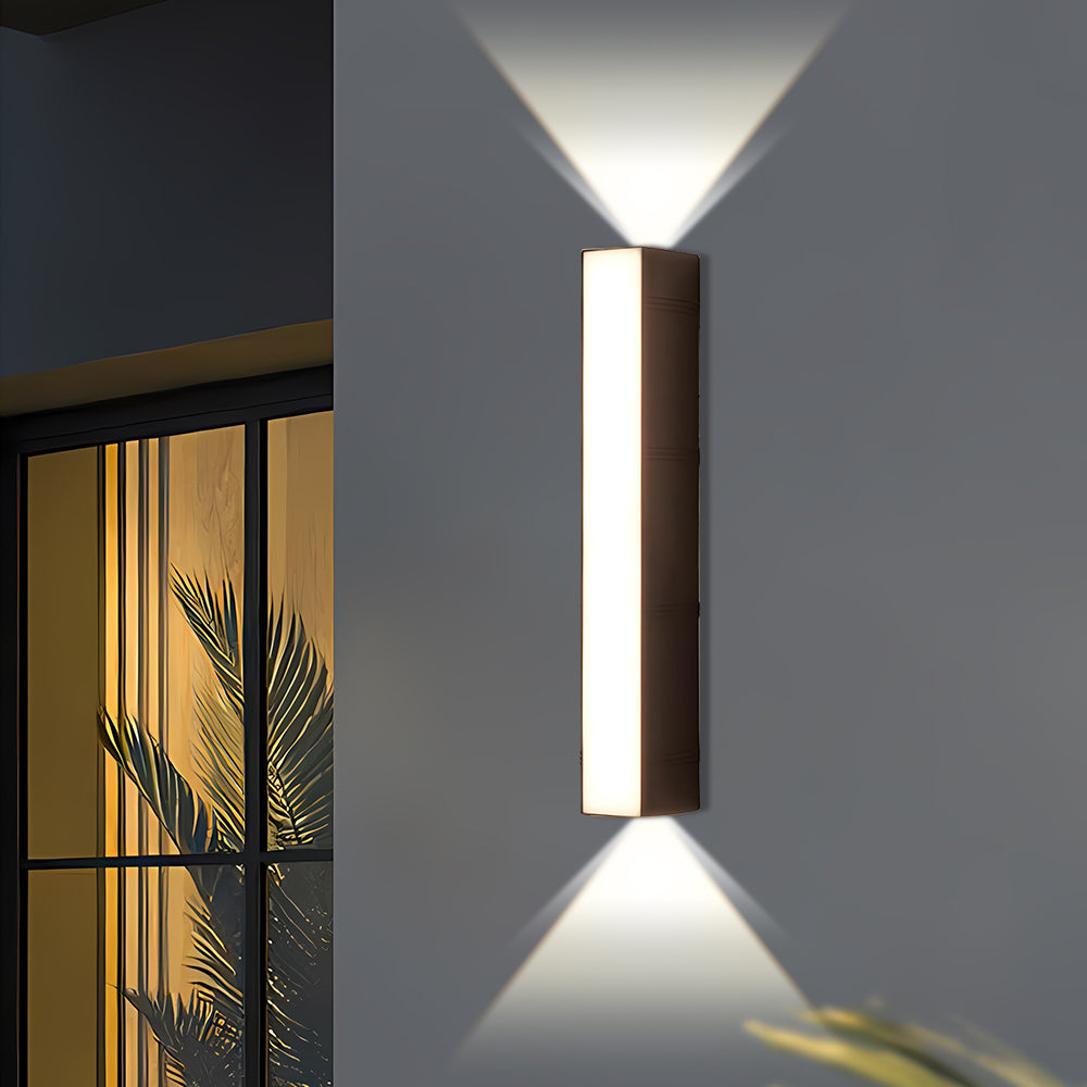 Black peqi architectural tube LED sconce mounted on a grey wall near a patio window