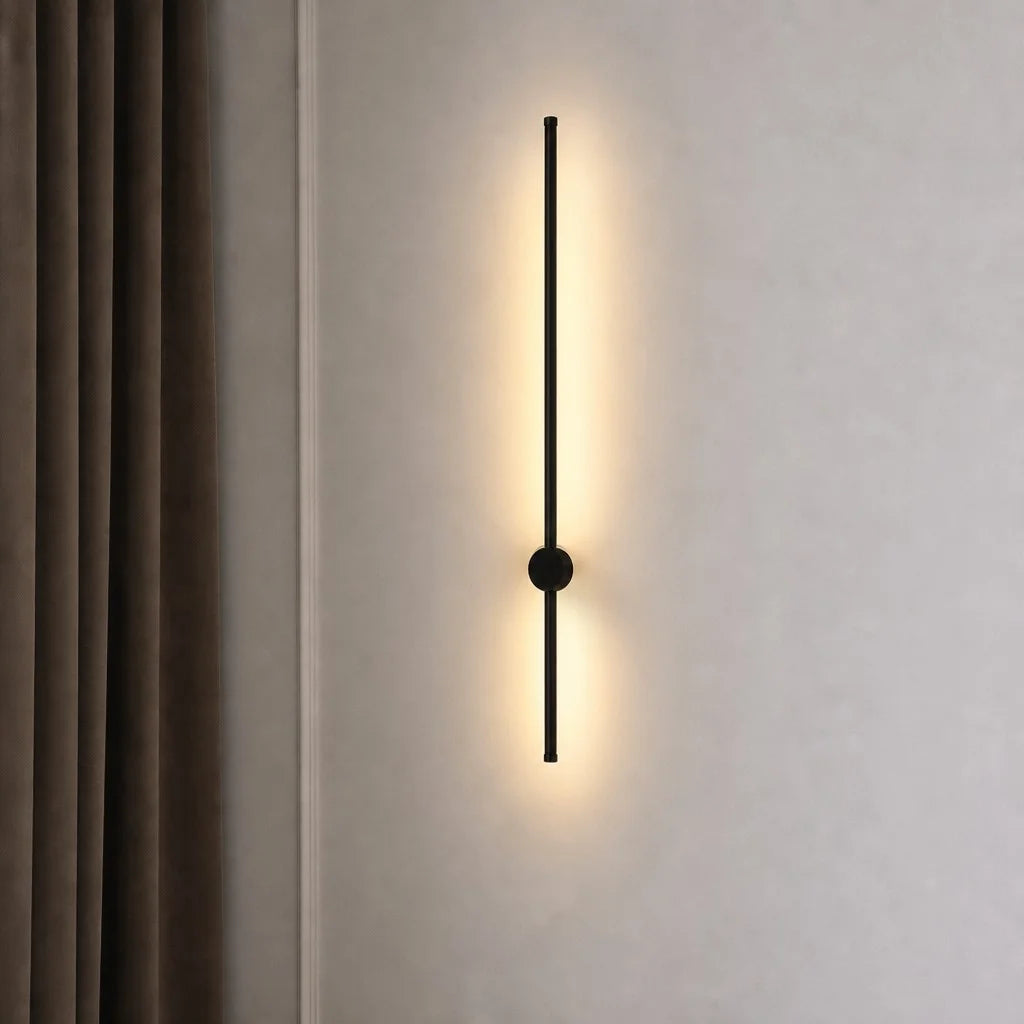 Minimalist pila black rotating tube wall lamp isolated on a plain wall, highlighting its slim silhouette