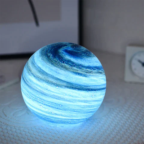Illuminated blue swirl glass orb pilo nightlight resting on a bright white textured surface