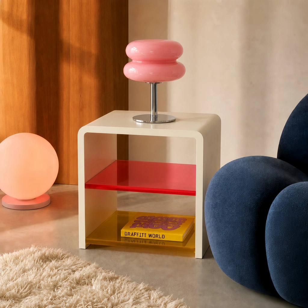 Pink Bauhaus glass side table light sitting on a retro acrylic stand next to a blue sofa