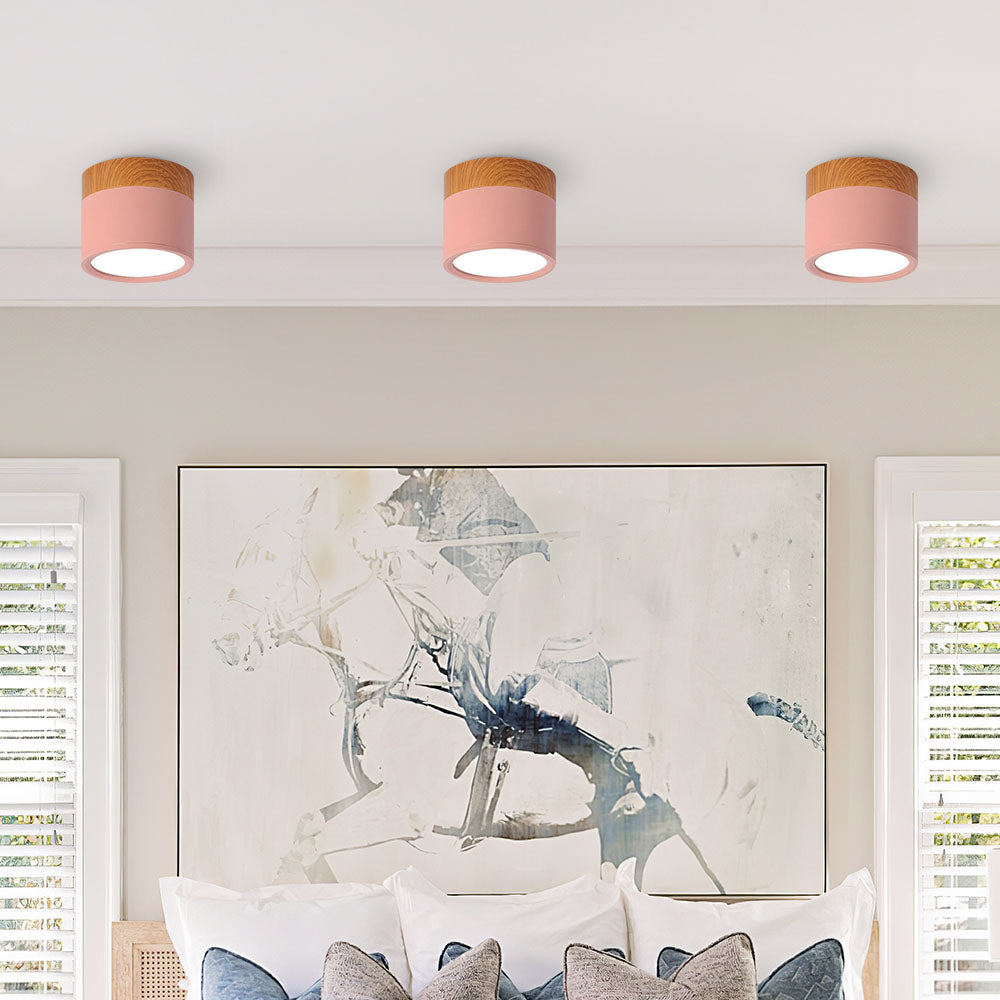 Row of soft pink cylinder flush ceiling lights installed above a bed