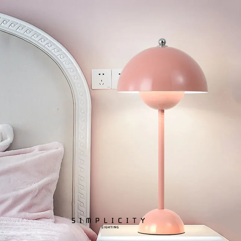 Pink macaron cordless bedside reading lamp casting a warm, romantic glow next to a white bed frame