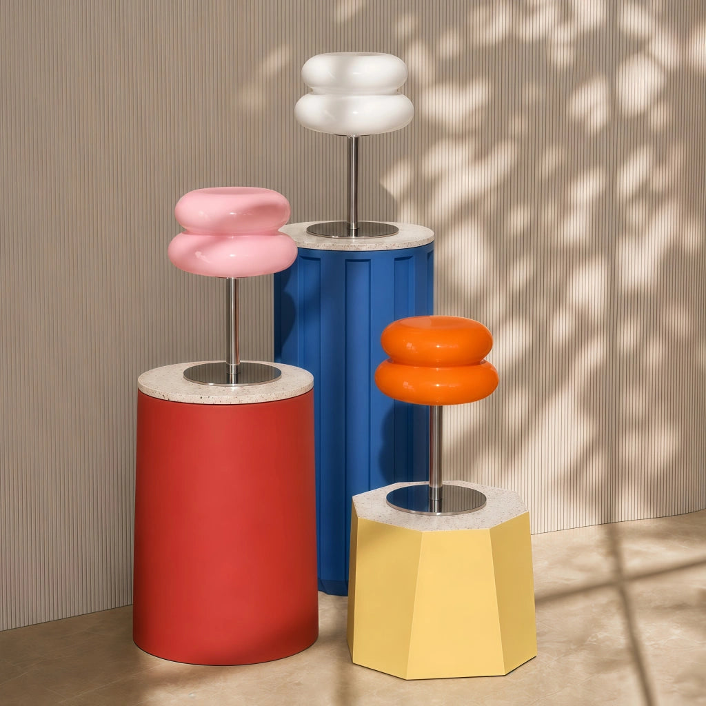 Pink and orange and white mid-century modern desk lamps styled on colourful geometric pedestals.