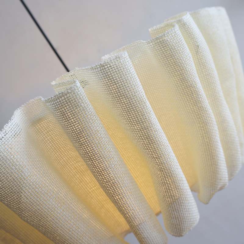 Close-up detail of the illuminated natural pleated fabric lampshade showcasing its organic texture