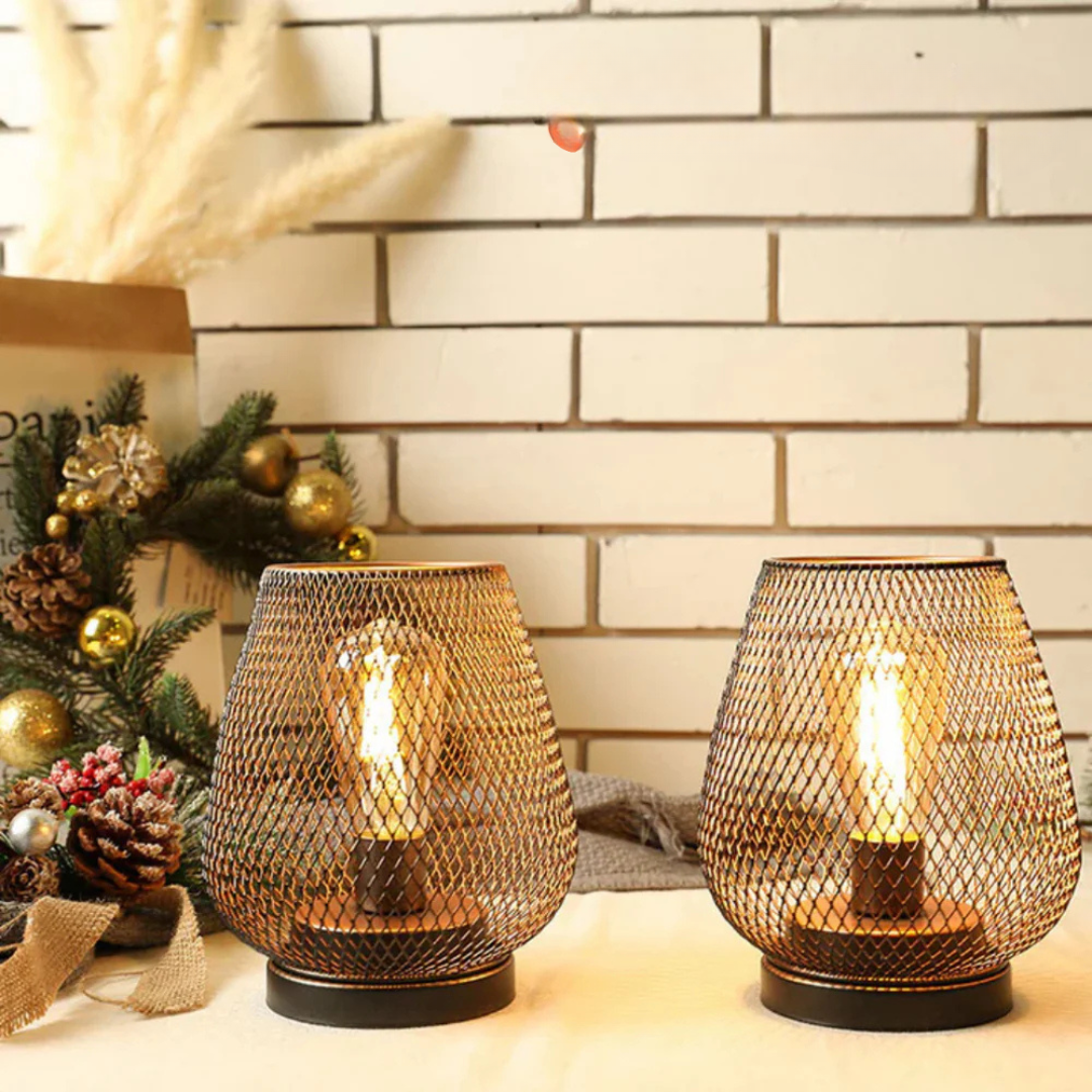 Portable metal cage lanterns acting as elegant ambient lighting next to festive decor and a white brick wall