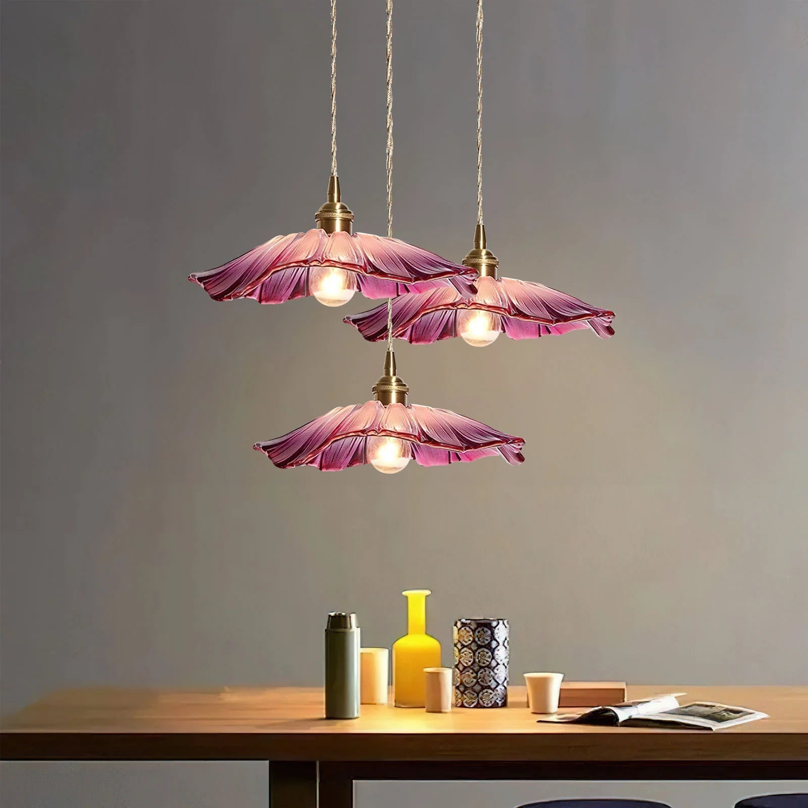 Cluster of three purple retro glass pendant lamps hanging over a wooden table