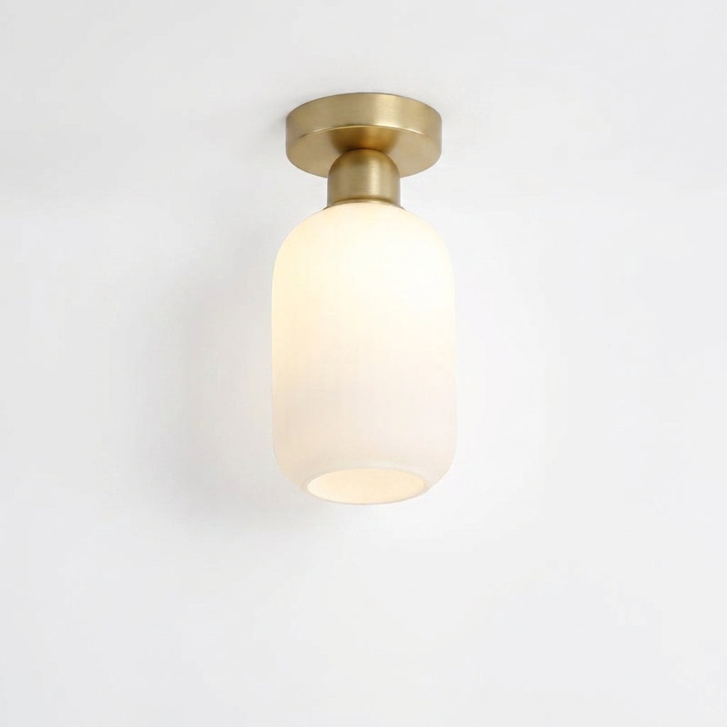 Qavlu ceiling light with a ribbed frosted capsule-shaped glass shade and brushed gold canopy, on white background